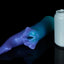 Fantasy shark-inspired silicone stroker in a gradient of teal to purple, featuring subtle ridges, twin pelvic fins framing the entrance, and a long, pointed tail, displayed on a black background. Next to the stroker is a grey soda can for scale.