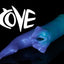 Fantasy shark-inspired silicone stroker titled "COVE" in a gradient of teal to purple, featuring subtle ridges, twin pelvic fins framing the entrance, and a long, pointed tail, displayed on a black background.